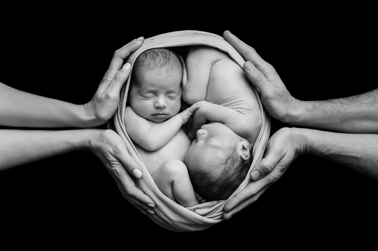 Jumeaux nouveau-nés endormis dans les mains de leurs parents — noir et blanc
